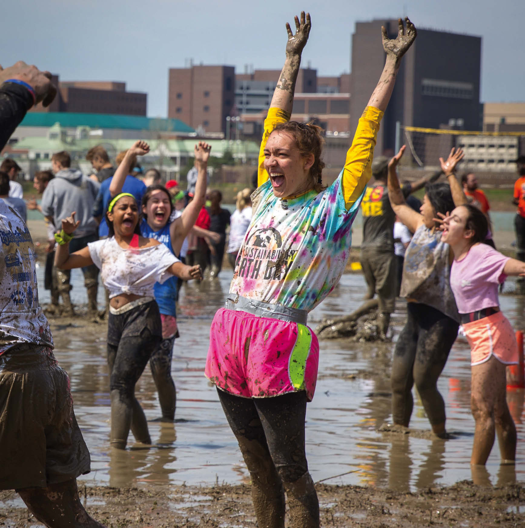 Student celebrating a point at Oozefest while playing volleyball in the mud.