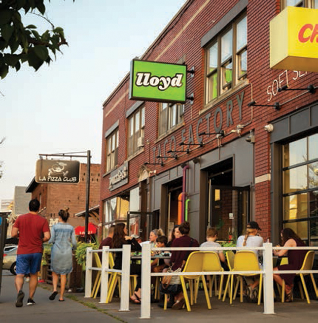 People eating and walking past Lloyd restaurant in North Buffalo.